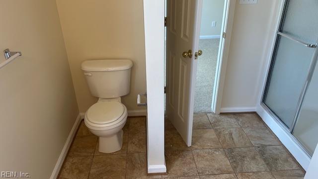 bathroom with an enclosed shower, baseboards, and toilet