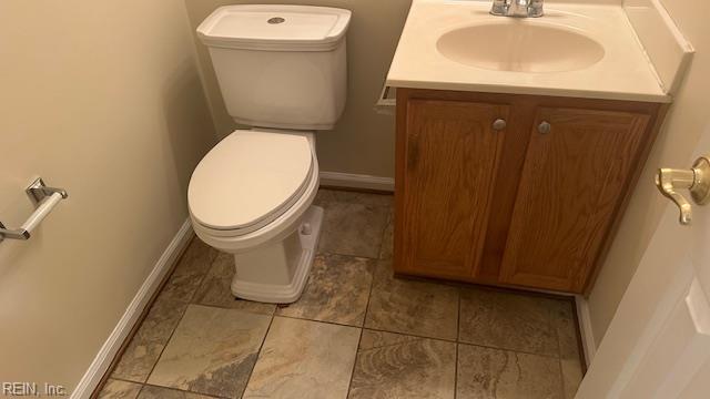 bathroom with toilet, baseboards, and vanity