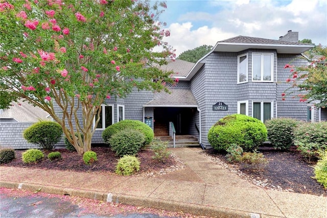traditional-style house featuring a chimney and a shingled roof