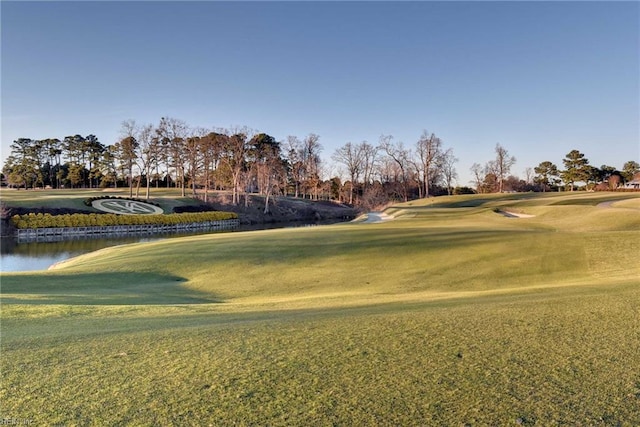 surrounding community with a water view, golf course view, and a lawn
