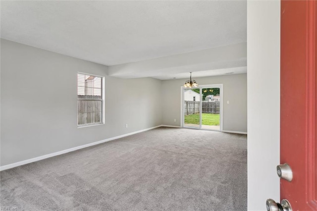 unfurnished room featuring a chandelier, carpet floors, and baseboards