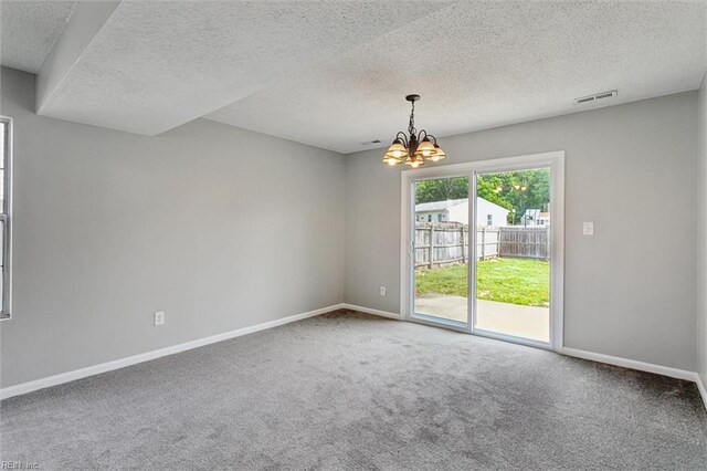 spare room featuring a chandelier, carpet flooring, baseboards, and a textured ceiling