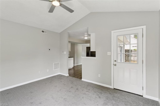 unfurnished living room featuring a ceiling fan, dark colored carpet, lofted ceiling, and baseboards