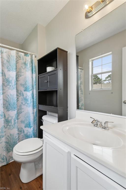 full bath featuring toilet, wood finished floors, vanity, and a shower with shower curtain