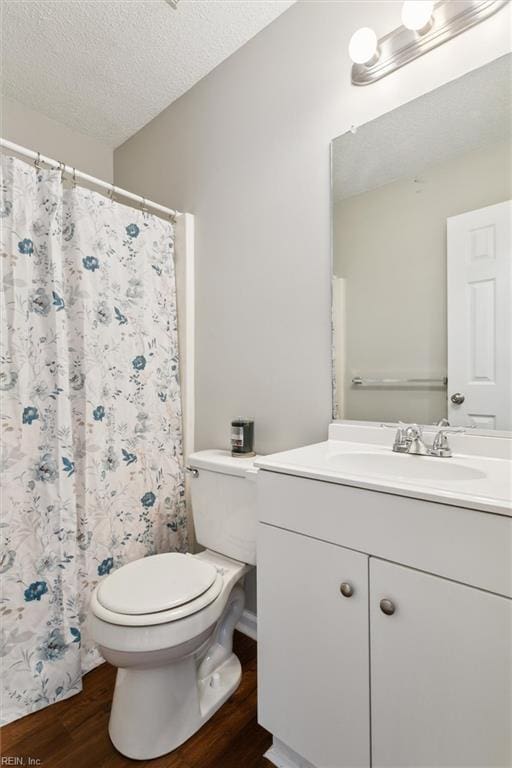 bathroom with wood finished floors, toilet, vanity, a textured ceiling, and a shower with shower curtain