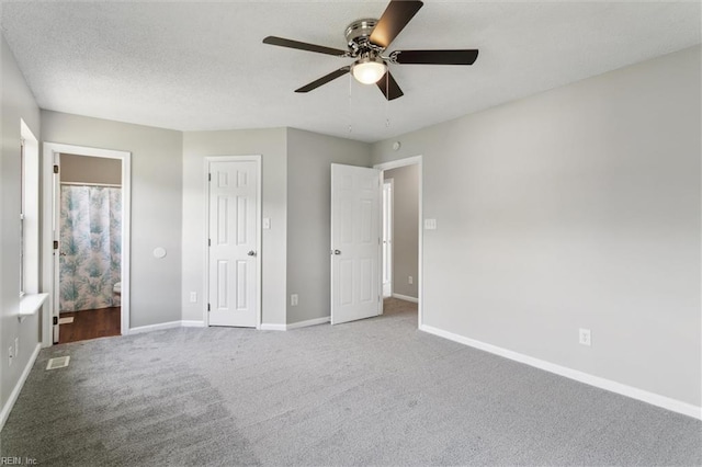 unfurnished bedroom featuring carpet, baseboards, ensuite bath, and ceiling fan