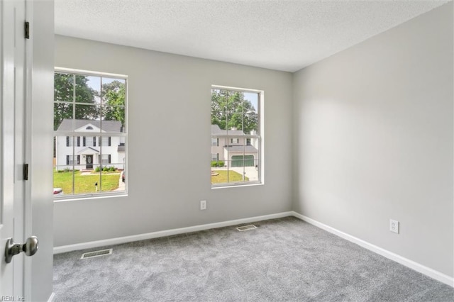 empty room featuring carpet flooring, a textured ceiling, and baseboards