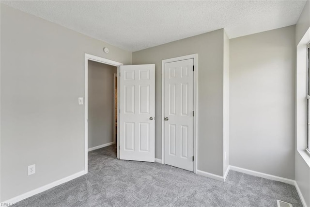 unfurnished bedroom with carpet, a textured ceiling, baseboards, and a closet