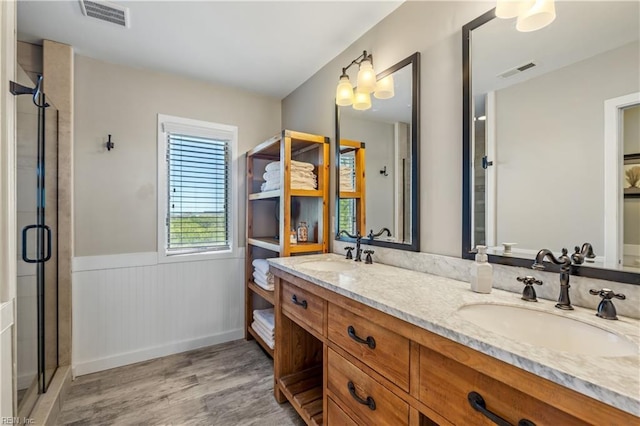 full bathroom with a wainscoted wall, visible vents, wood finished floors, and a sink
