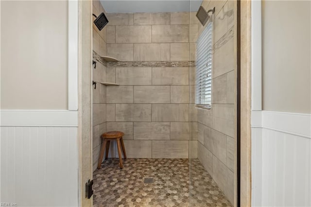 bathroom featuring a wainscoted wall and tiled shower
