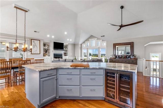 kitchen with ceiling fan with notable chandelier, open floor plan, gray cabinets, lofted ceiling, and wine cooler