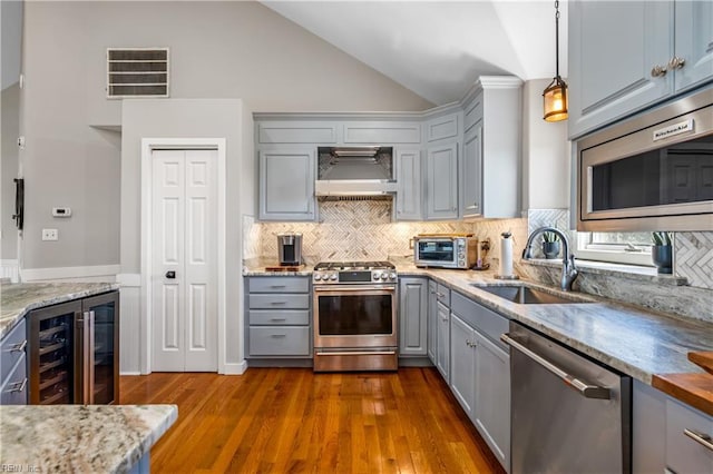 kitchen featuring visible vents, a sink, wall chimney range hood, stainless steel appliances, and gray cabinets
