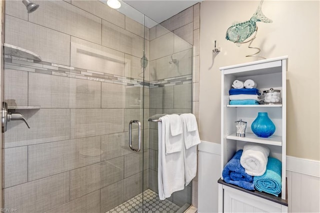 bathroom featuring a wainscoted wall and a shower stall
