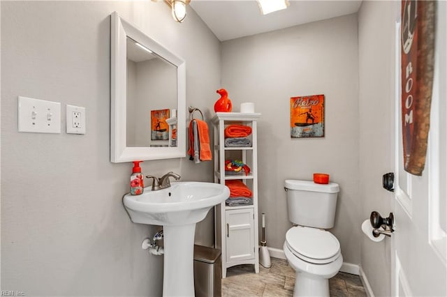 half bathroom featuring toilet and baseboards