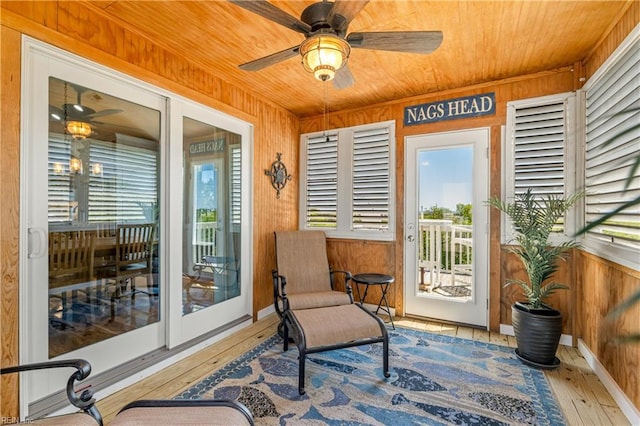 sunroom with a healthy amount of sunlight, wood walls, wood-type flooring, and wooden ceiling