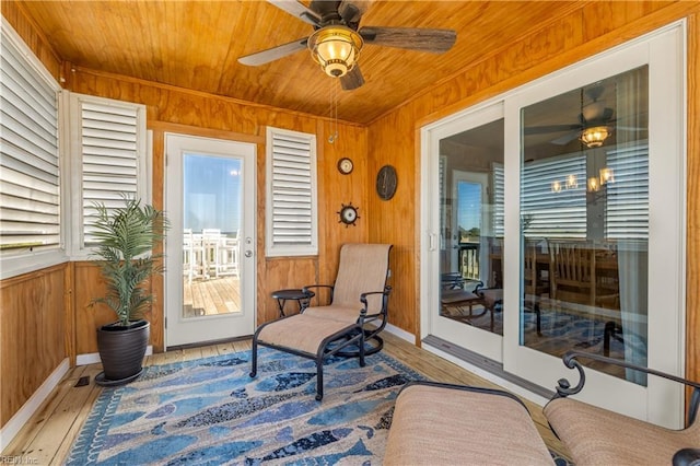 sunroom featuring wooden walls, ceiling fan, and hardwood / wood-style flooring