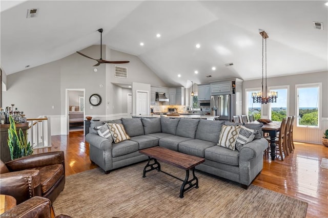 living area with light wood-style floors, visible vents, wainscoting, and high vaulted ceiling