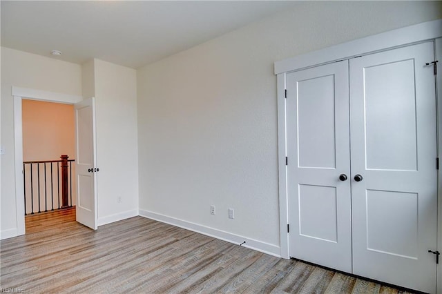 unfurnished bedroom with baseboards, a closet, and wood finished floors