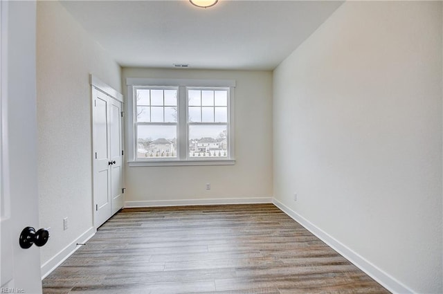 empty room featuring baseboards, visible vents, and wood finished floors