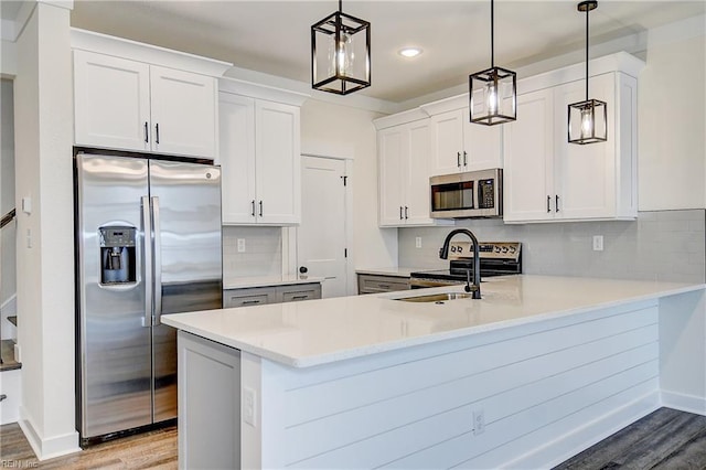 kitchen with a peninsula, stainless steel appliances, light wood-type flooring, light countertops, and decorative backsplash