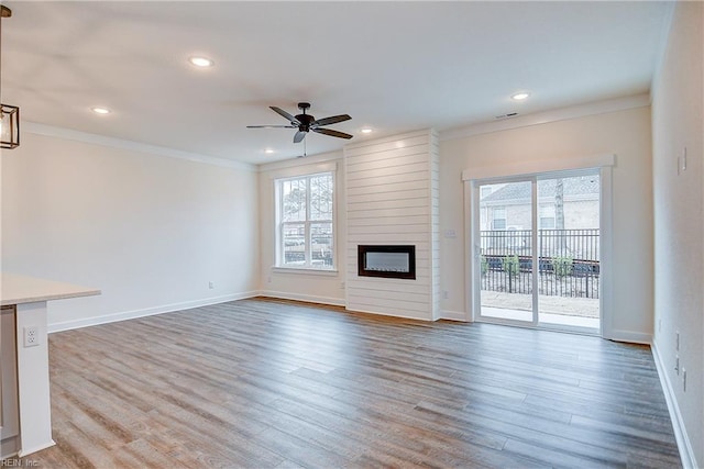 unfurnished living room with baseboards, ceiling fan, crown molding, and wood finished floors