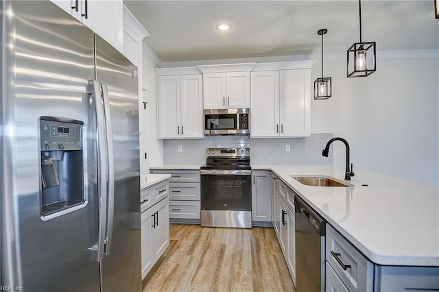 kitchen with a peninsula, a sink, light wood-type flooring, appliances with stainless steel finishes, and decorative backsplash