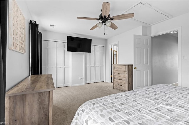 bedroom with attic access, multiple closets, carpet, baseboards, and ceiling fan