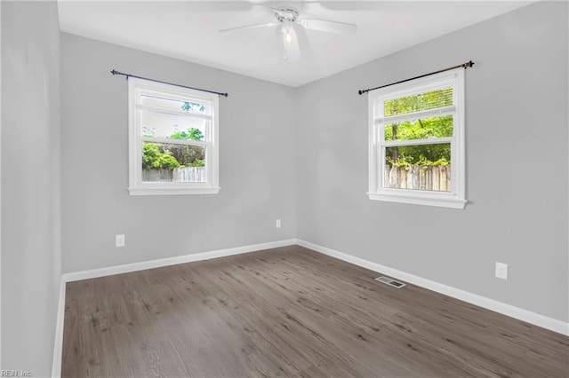 spare room with baseboards, ceiling fan, visible vents, and wood finished floors