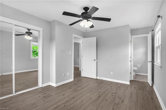 unfurnished bedroom with a closet, wood finished floors, baseboards, and ceiling fan