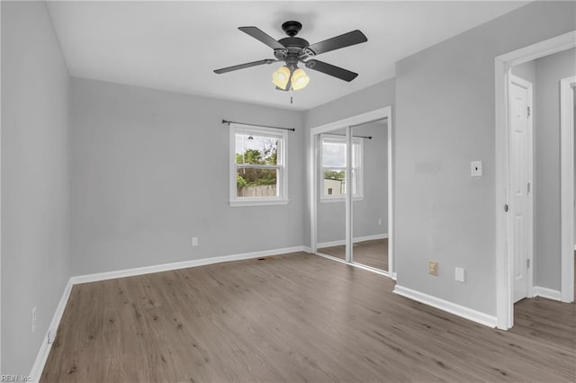 unfurnished bedroom with baseboards, a closet, ceiling fan, and wood finished floors