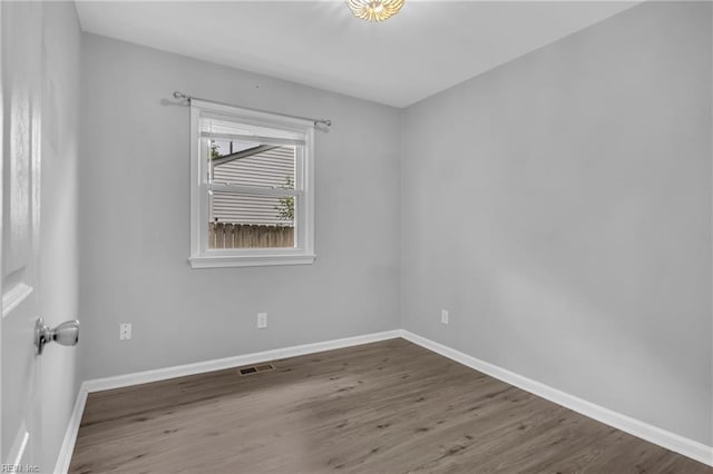 spare room featuring baseboards, visible vents, and wood finished floors