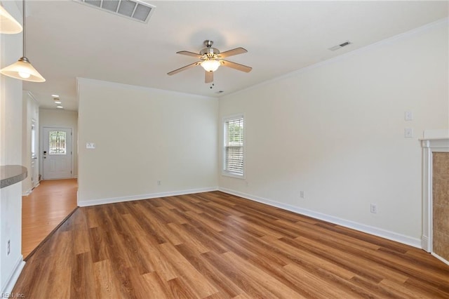 unfurnished room with light wood finished floors, a ceiling fan, visible vents, baseboards, and ornamental molding