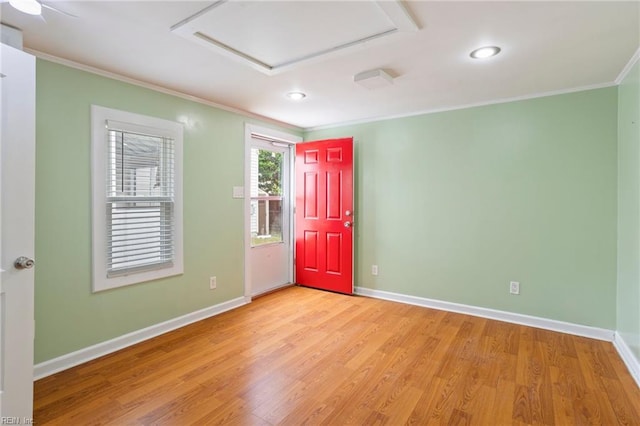 spare room featuring light wood-style flooring, attic access, crown molding, baseboards, and recessed lighting