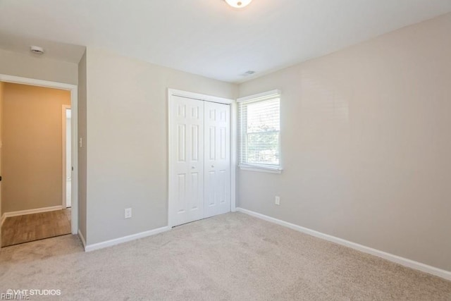 unfurnished bedroom featuring baseboards, a closet, and carpet