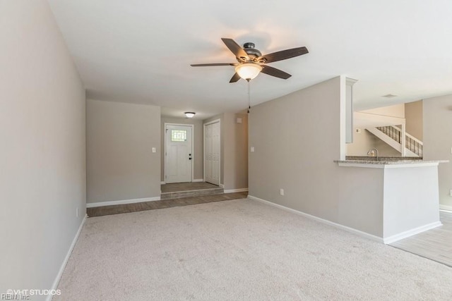 unfurnished living room with a ceiling fan, baseboards, and carpet flooring
