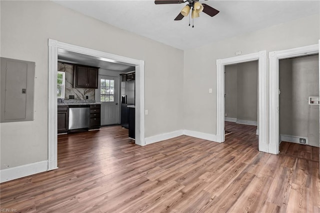 unfurnished living room featuring electric panel, ceiling fan, wood finished floors, and baseboards