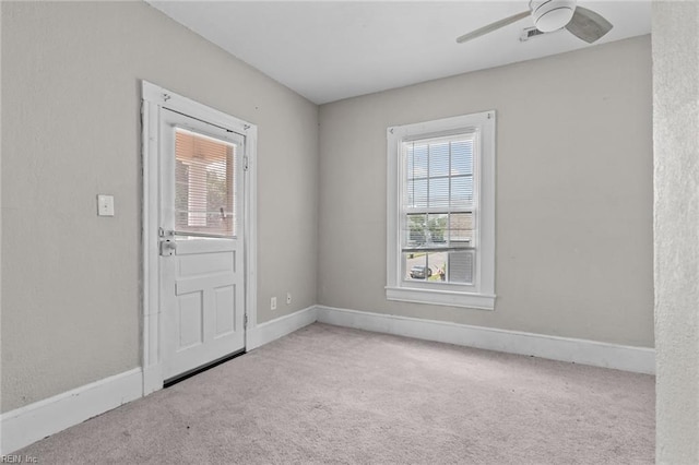 carpeted empty room with plenty of natural light, a ceiling fan, and baseboards