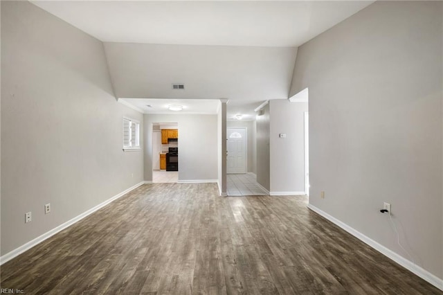 unfurnished living room with baseboards, wood finished floors, and lofted ceiling