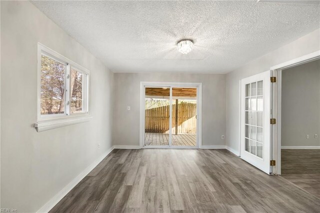 unfurnished room featuring wood finished floors, a textured ceiling, and baseboards