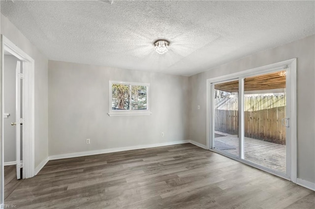 unfurnished bedroom with access to exterior, wood finished floors, a textured ceiling, baseboards, and a chandelier