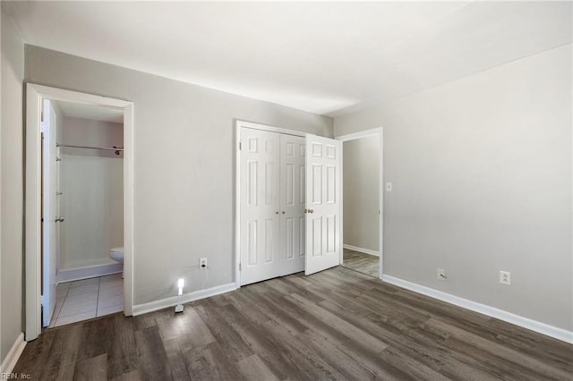 unfurnished bedroom featuring wood finished floors, baseboards, and ensuite bathroom