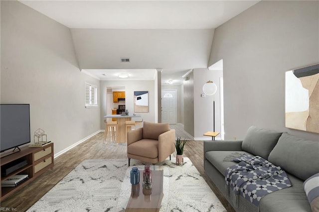 living area featuring baseboards, wood finished floors, and lofted ceiling
