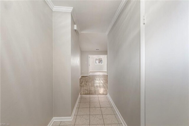 corridor featuring ornamental molding, baseboards, and light tile patterned floors