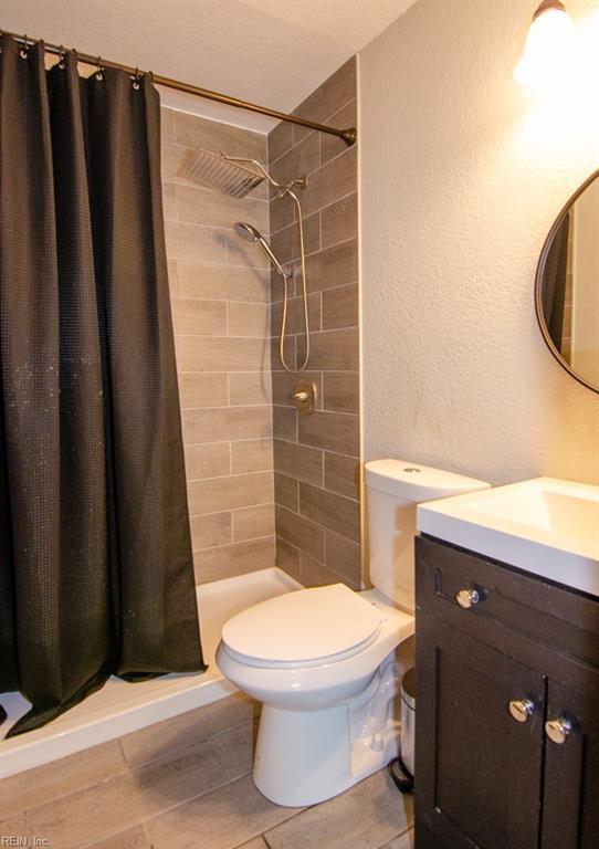 8123 Kenwood Dr, Norfolk, VA 23518 - full bath featuring toilet, vanity, a stall shower, wood finished floors, and a textured wall