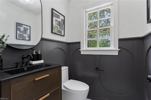 bathroom with a wealth of natural light, a decorative wall, and a wainscoted wall