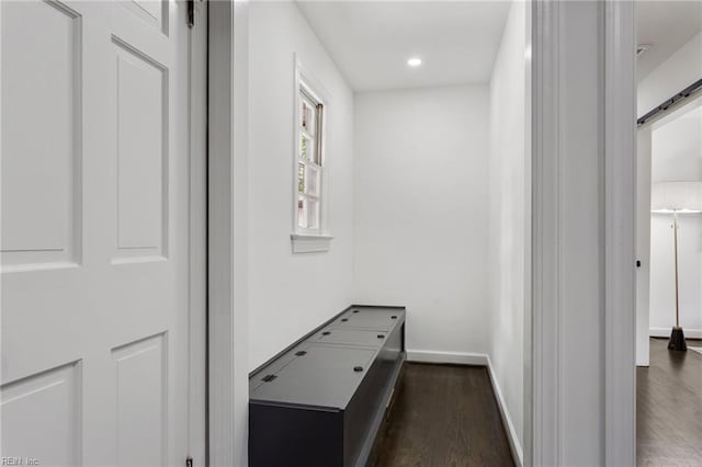 corridor featuring a barn door, baseboards, dark wood-style floors, and recessed lighting