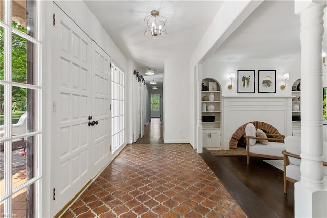 entrance foyer featuring a chandelier, baseboards, stone finish floor, and plenty of natural light