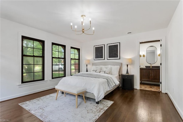 bedroom with baseboards, ensuite bathroom, dark wood finished floors, a sink, and a chandelier