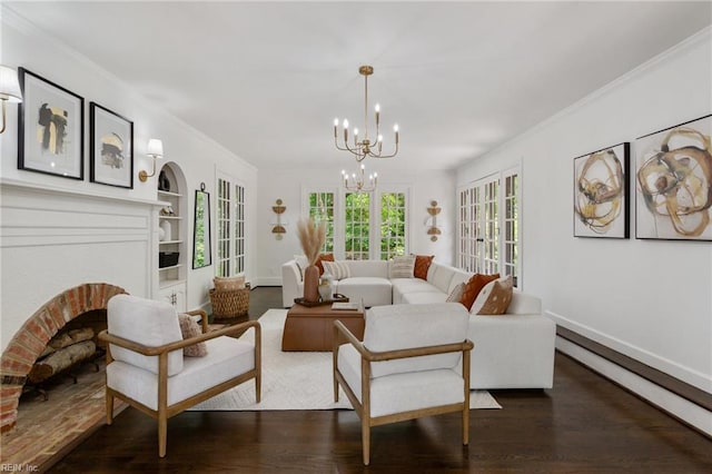 living room featuring wood finished floors, ornamental molding, built in shelves, a fireplace, and an inviting chandelier