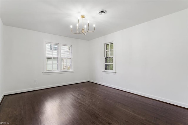 unfurnished room featuring baseboards, dark wood-style flooring, a notable chandelier, and visible vents